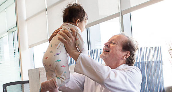 Dr. Samuel Wood, MD, PhD, Medical Director of Great Beginnings Surrogacy, holding a baby born through GBSS